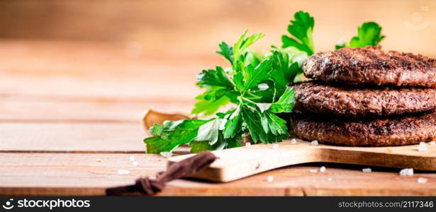 Burger grill on a cutting board. On a wooden background. High quality photo. Burger grill on a cutting board.