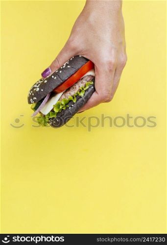 burger held front yellow background