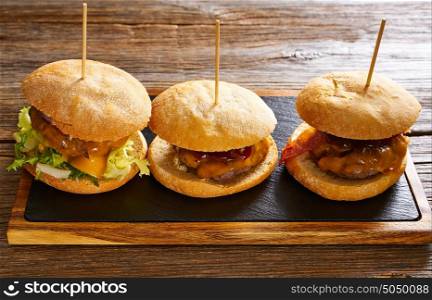 Burger in a row on a slate board and wood table