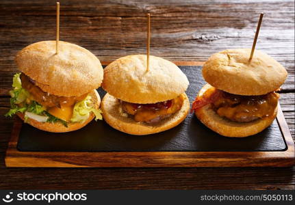 Burger in a row on a slate board and wood table