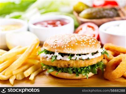 burger with chicken and fries on wooden table