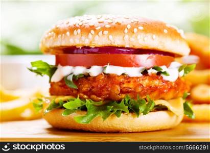 burger with chicken and fries on wooden table