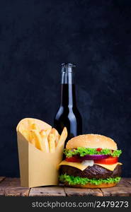 Burger with french fries and drink on wooden table