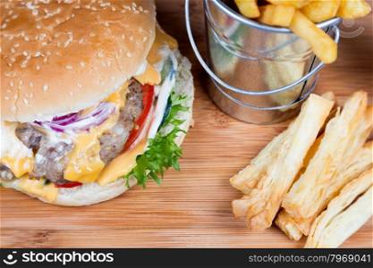 burger with fried potatos in bucket serving on wooden board