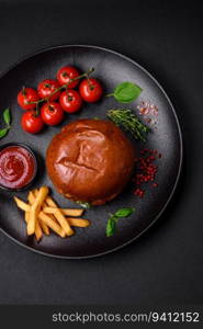 Burger with juicy beef cutlet, cheese, tomatoes, salt, spices and herbs on a dark concrete background