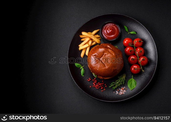 Burger with juicy beef cutlet, cheese, tomatoes, salt, spices and herbs on a dark concrete background