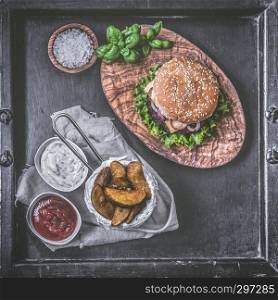 Burger with potato wedges on dark background