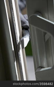 Burglar breaking into house, close-up of crowbar