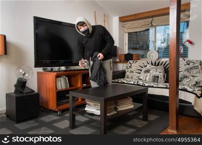 burglar robbing a house. Burglar stealing stuff in a living room