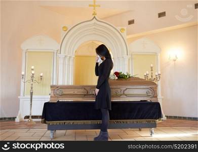 burial, people and mourning concept - sad woman with coffin at funeral in orthodox church. sad woman with coffin at funeral in church