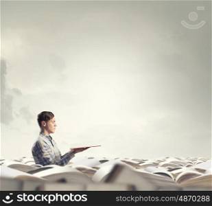 Buried in knowledge and studying. Young man sitting in pile of old books