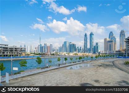 Burj Khalifa with lake or river and bridge in Dubai Downtown skyline, United Arab Emirates or UAE. Financial district and business area in urban city. Skyscraper buildings with blue sky. Reflection.