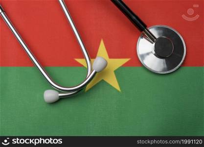 Burkina Faso flag and stethoscope. The concept of medicine. Stethoscope on the flag as a background.. Burkina Faso flag and stethoscope. The concept of medicine.