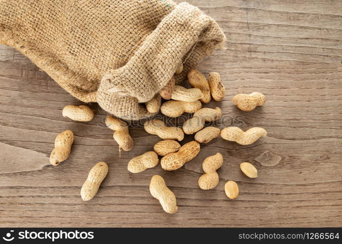 Burlap sack and Peanuts on rustic wooden table. Arachis hypogaea