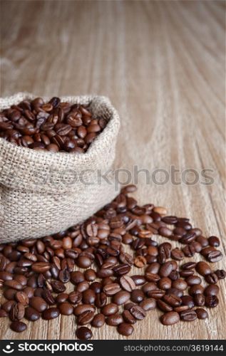 burlap sack of coffee beans on old wooden table.Shallow DOF