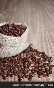 burlap sack of coffee beans on old wooden table.Shallow DOF