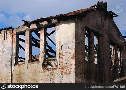 Burned old house, destroyed roof, blue sky