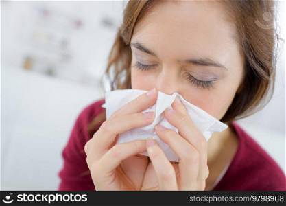 burnette woman blowing nose into tissue