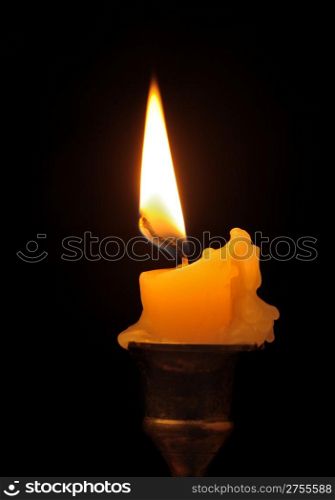 Burning candle. An ancient candlestick, a dark background