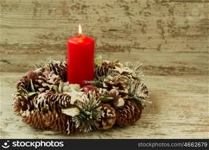 Burning candle in a Christmas setting with seasonal decorations.