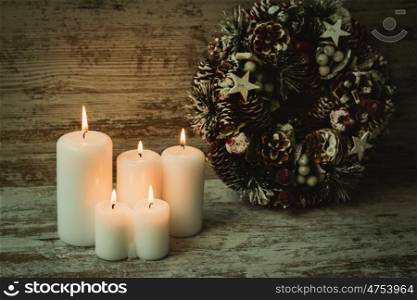 Burning candle in a Christmas wreath with seasonal decorations.