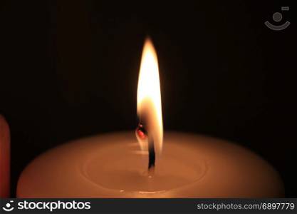 Burning candle in closeup, big flame and melted wax