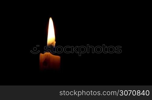 Burning candle isolated on black background
