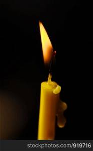 Burning candle on black background. Burning candle on black background. Candle light. The flame of candle light.