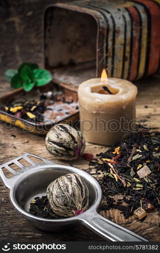 burning candle on the background of scattered tea with lime and mint in rustic style.Selective focus. tea brew with lime and mint on wooden background