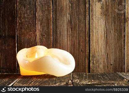 Burning candle on wooden table