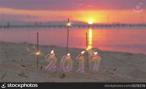 Burning candles 2017 and sparklers on the beach with sea and sunset in background