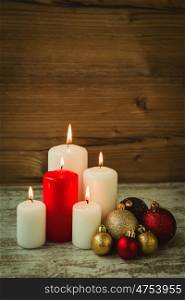 Burning candles and balls for Christmas on a wooden background