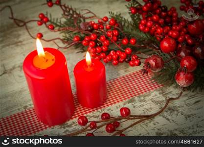 Burning candles in a Christmas setting with seasonal decorations.