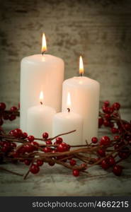 Burning candles in a Christmas setting with seasonal decorations.