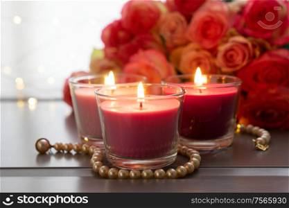Burning candles with rose fresh flowers bouquet on gray table, close up home interior details. fresh rose flowers on gray