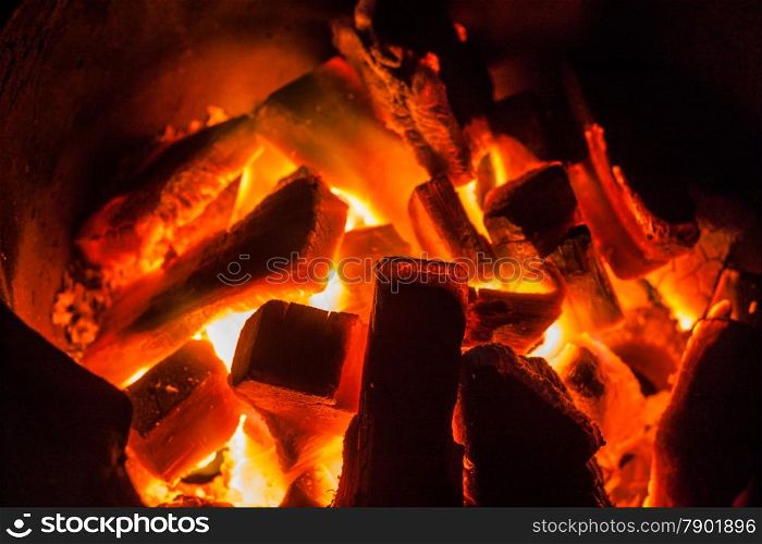 Burning charcoal in stove on dark background