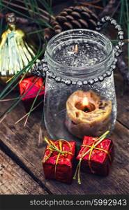 Burning Christmas candle. Christmas candle in the spilled wax in stylish glass candle holder