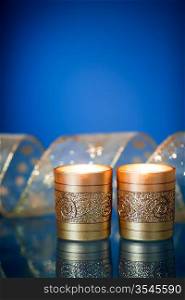 Burning Christmas candles and gold ribbon on blue background