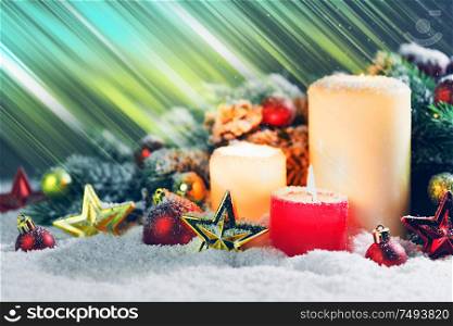 Burning christmas candles with red and golden decorative stars , baubles , pine cones and green branches on snow. Christmas candles with decoration