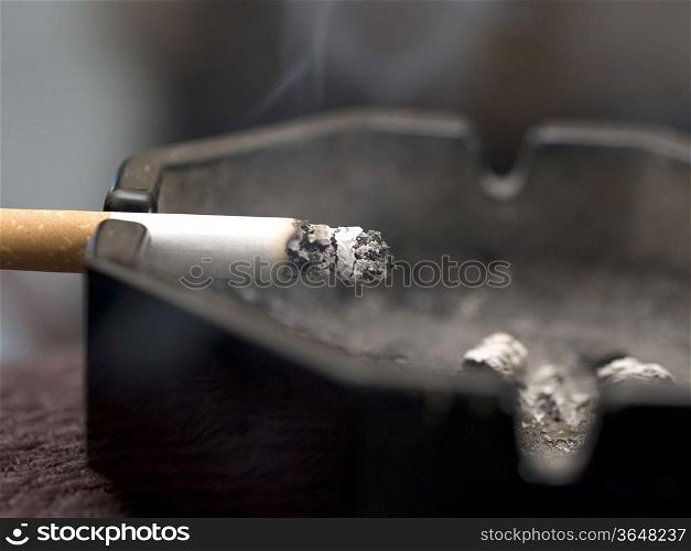 Burning cigarette resting on ashtray