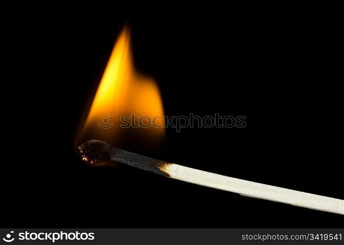 Burning flame on a matchstick over a black background