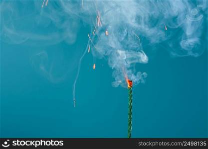 Burning fuse wick cord with sparks and smoke on blue background
