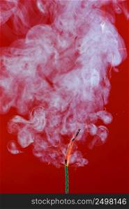Burning fuse wick cord with sparks and smoke on red background