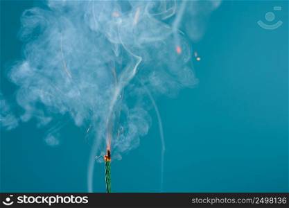 Burning green fuse wick cord with sparks and smoke on blue background