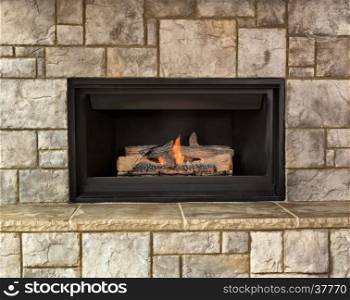 Burning natural gas fireplace surround by stone