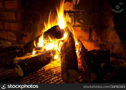 burning round logs in fireplace against brick smoked wall