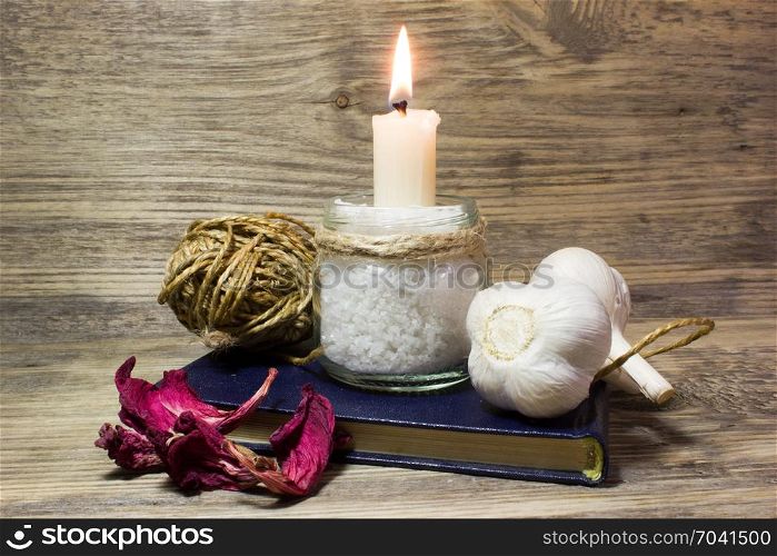Burning white candle in glass jar on wooden background
