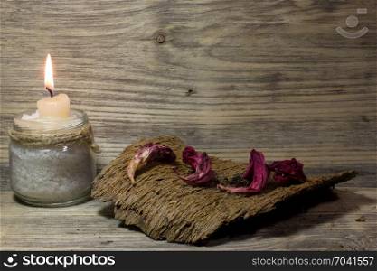 Burning white candle in glass jar on wooden background