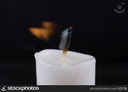 burning white candle on a black background