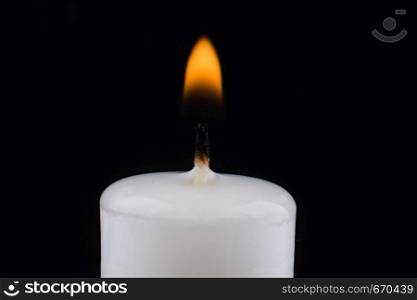 burning white candle on a black background